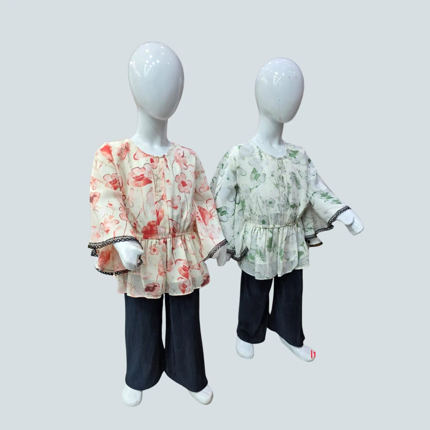 Two mannequins wearing floral tops and black pants on a light gray background
