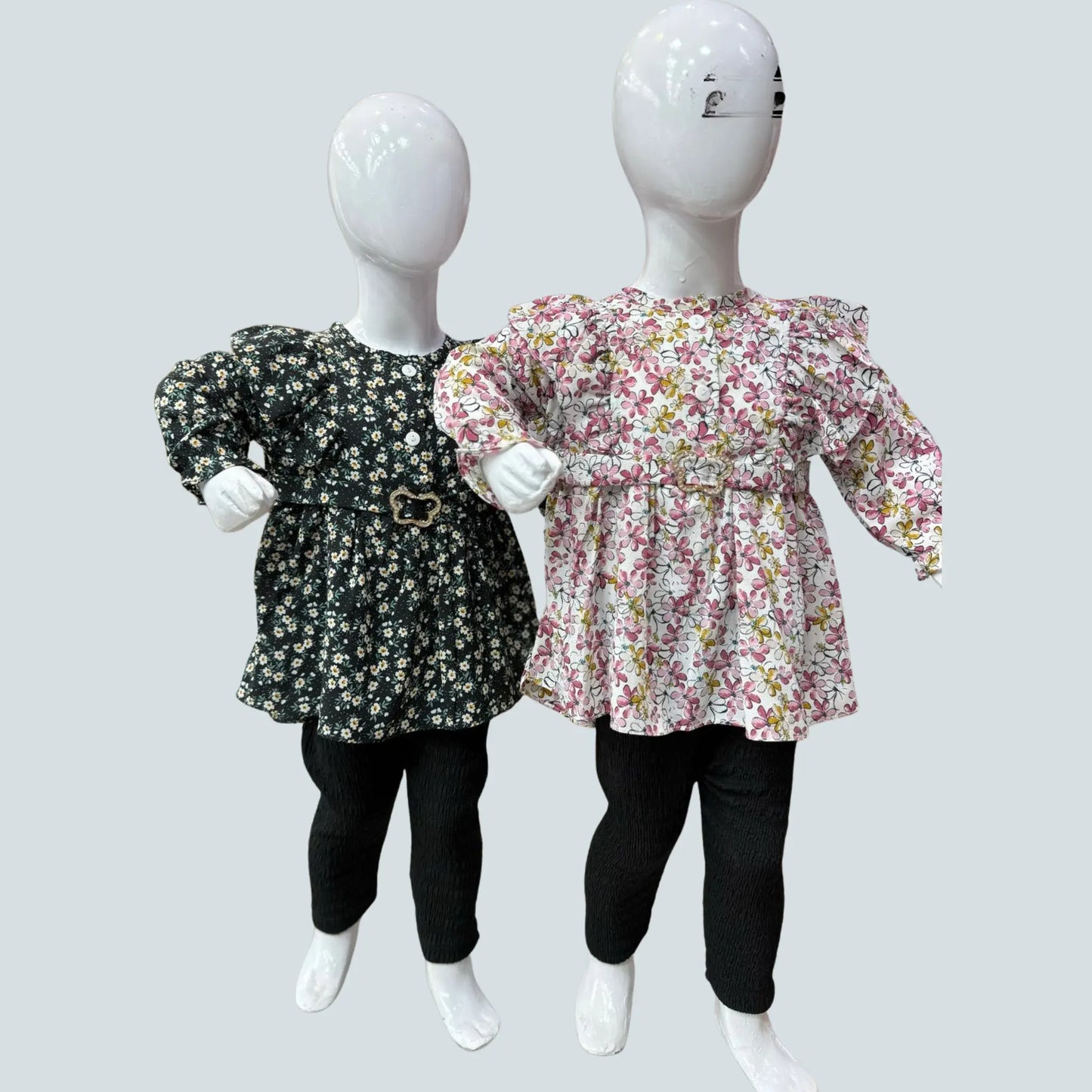 Two mannequins wearing floral tops and black pants on a light gray background