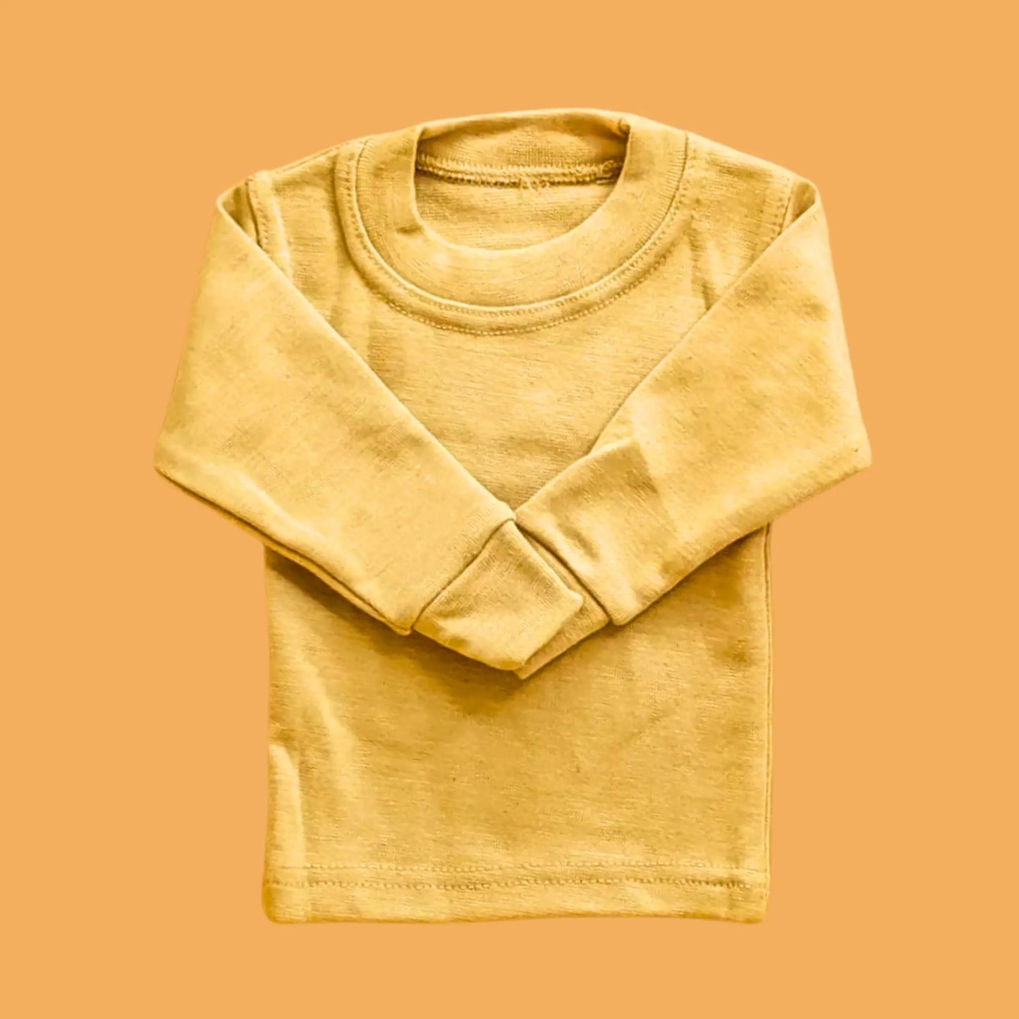 Folded yellow long-sleeve shirt on a matching orange background
