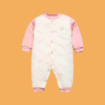 Baby onesie with pink sleeves and patterned body on a mustard yellow background