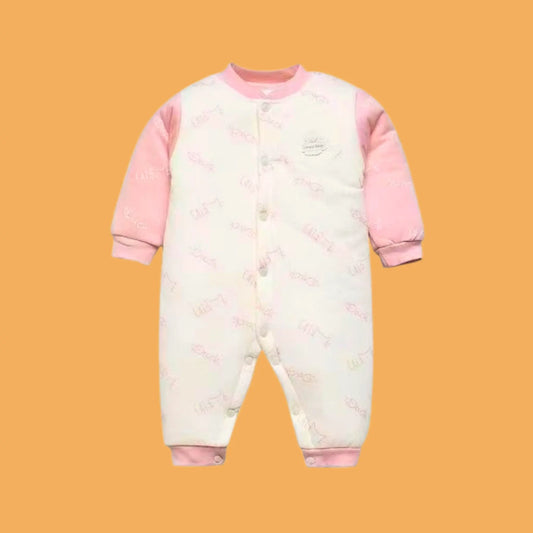 Baby onesie with pink sleeves and patterned body on a mustard yellow background