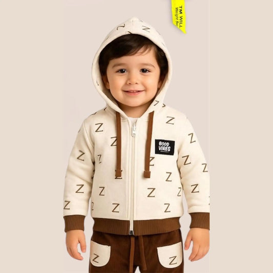 Child wearing a cream hoodie with letter 'Z' patterns and brown pants on a plain background